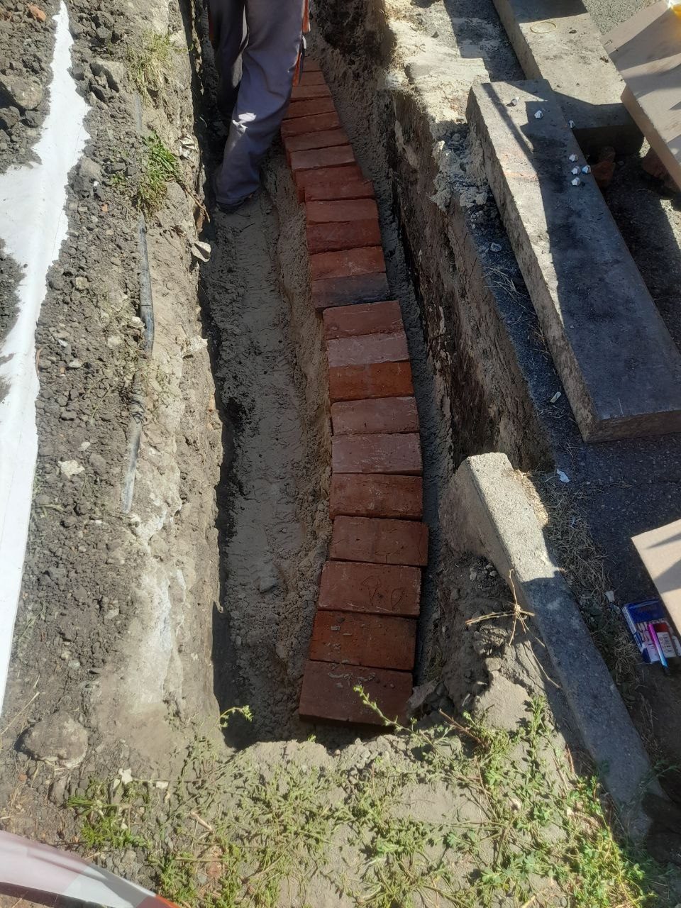 Укладання захисної цегли над кабелем у траншеї